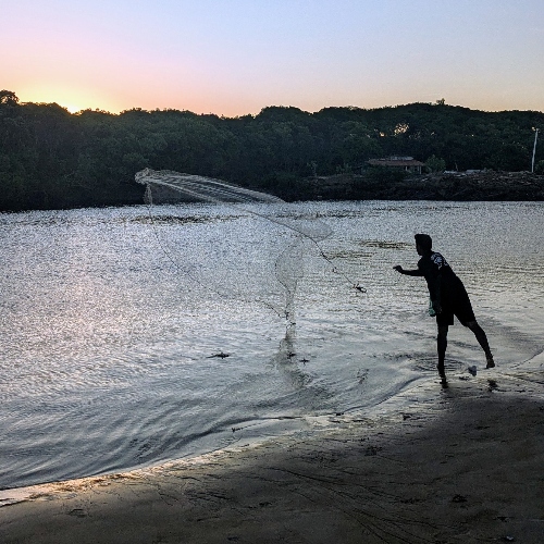 A fisherman casts his net into the Pacoti River at its pass by Caça e Pesca favela — in the urban periphery of Fortaleza.