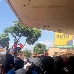 People waiting to hear Martha Karua, candidate for deputy president for the Azimio la Umoja coalition in Kenya’s 2022 elections, speak at a rally in Nyeri, Kenya. Behind them is a poster for the current deputy president, William Ruto, who is the president