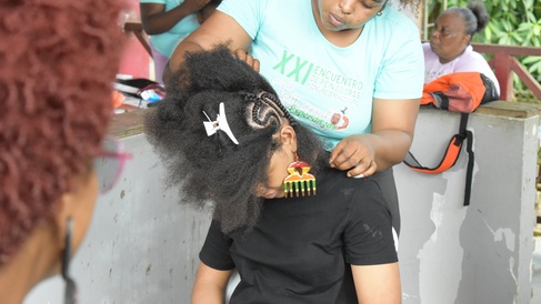 A traditional hairdresser braids her model's hair